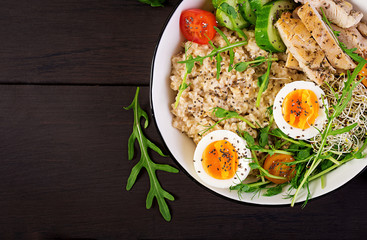 Fresh salad. Breakfast bowl with oatmeal, chicken fillet, tomato, lettuce, microgreens and boiled egg. Healthy food. Vegetarian buddha bowl. Top view