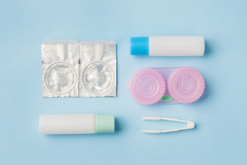Contact lenses, tweezers and a container for storing lenses, containers for solution and moisturizing drops. Close up. Selective focus.