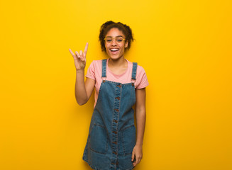 Young black african american girl with blue eyes doing a rock gesture