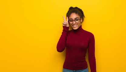 Young black african american girl with blue eyes fun and happy doing a gesture of victory