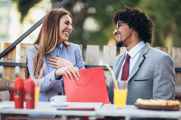 Coffee break after shopping. Couple in love drinking coffee in the cafe and sharing new purchases with each other.