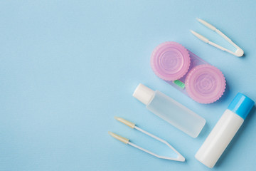 Contact lenses, tweezers and a container for storing lenses, containers for solution and moisturizing drops. Close up. Selective focus.