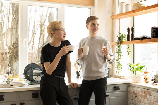 Portrait of international gay couple in casual clothes in the morning at home in the kitchen