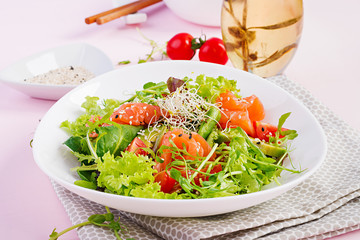 Diet menu. Healthy salad of fresh vegetables - tomatoes, avocado, arugula, seeds and salmon on a bowl. Vegan food.