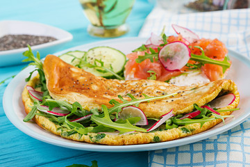 Breakfast. Omelette with radish, green arugula and sandwich with salmon on white plate.  Frittata - italian omelet.