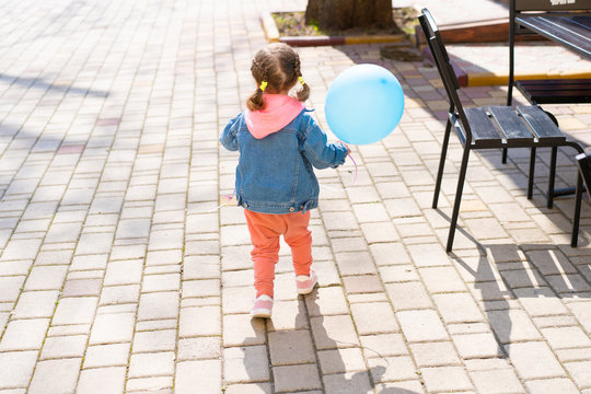 The little girl runs away from her parents with an inflatable ball in their hands.
