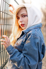 Young Woman with temporary painted flowers on the face. teenage girl with long blond hair wear jeans jacket and hoody