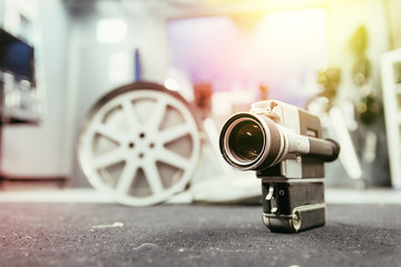 Movie production: vintage old movie camera on a desk, production studio in the background