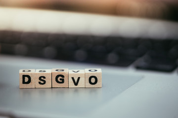 DSGVO: Wooden cubes with letters “DSGVO” lying on a laptop. Datenschutzgrundverordnung.