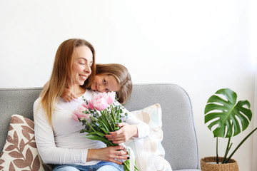 Cute little five year old girl giving her mom a present for mothers day. Adorable scene with daughter surprizing her mum. Close up, background, portrait.