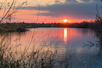 Fototapeta na wymiar Sunset or sunrise on the cloudy sky on lake