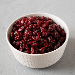 Dried cranberries in a bowl over gray background, side view. Close-up.
