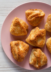 Home-baked cottage cheese biscuits on a pink plate over white wooden background, top view. Flat lay, overhead. Close-up.