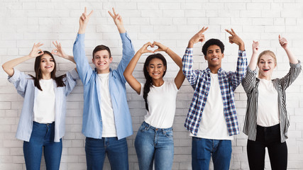 Teen friends gesturing with hands over white wall