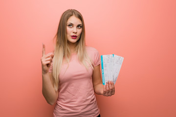 Young pretty russian girl having a great idea, concept of creativity. She is holding an air tickets.