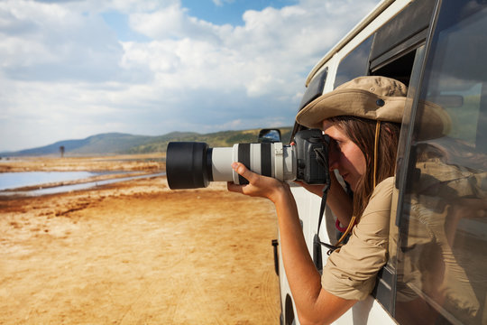 Girl taking photo of African savannah from jeep
