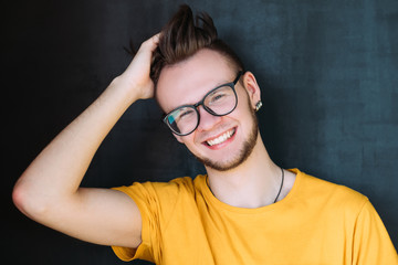 Millennial guy portrait. Happy young man in glasses smiling broadly and messing hair. Lighthearted...
