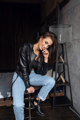Fototapeta na wymiar Sexy beautiful brunette in leather jacket and jeans posing in the room