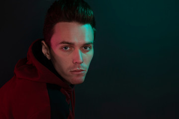 Fototapeta premium Studio portrait of a sad guy in a hoodie on black background.