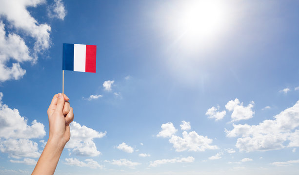 Woman's hand holding French flag over the flagpole