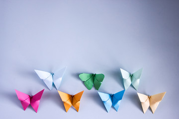 Origami butterflies of colored paper on a blue background. Children's creativity. Art of paper....