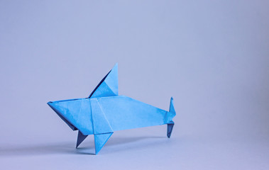 Blue paper origami shark on blue background, copy space