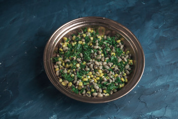 Appetizers dry cowpea salad with corns and parsley on blue background
