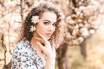 Naklejka premium Beautiful blonde girl with flowers in hair outdoors. Looking at camera. Spring season. 20s.