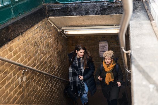 Two friends coming up the stairs and out of a subway station
