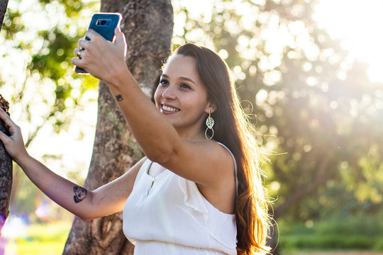 young girl taking selfie photos with her mobile phone in the park 