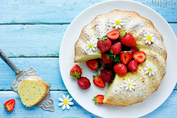 Classic vanilla bundt cake with strawberries and powdered sugar top view
