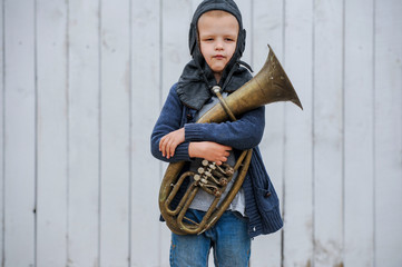 Slavic children from orphanage in old clothes gathered by parishioners of church play behind tall wooden fence with plastic auto painted in gray paint. Boys dreams about freedom, forest, river, plane