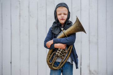 Slavic children from orphanage in old clothes gathered by parishioners of church play behind tall wooden fence with plastic auto painted in gray paint. Boys dreams about freedom, forest, river, plane