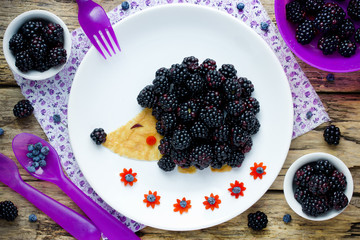 Fun and healthy breakfast for kids - edible hedgehog from pancake with peanut butter and fresh blackberry,  animal shaped food art idea