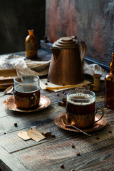 Two blue glasses in vintage copper cup holder on plates with hot drink (tea, coffee) 