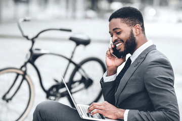 African-american businessman using laptop, having break outdoors