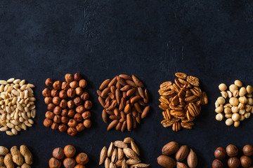 Various nuts on black stone table. Top view frame with copy space