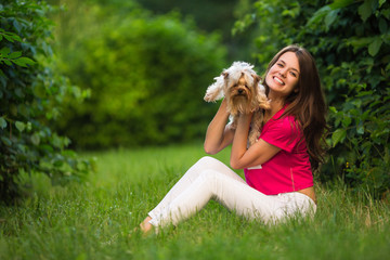 Beautiful woman play with dog sitting on grass in the green park.