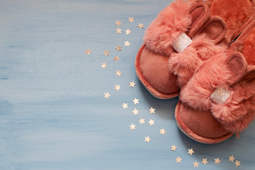 Slippers in the shape of a bunny with ears on a blue background.