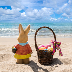 Easter bunny with color eggs on the ocean beach