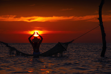 beautiful young woman silhouette with swing posing in the sea on sunset, maldivian romantic scenery