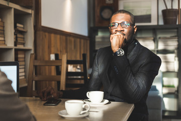 Young handsome dark-skinned businessman in a cafe with a cup of tea.