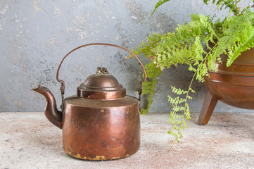 Antique copper kettle on concrete background.
