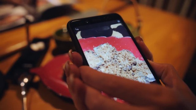 A woman takes a photograph dessert on a smartphone in a Japanese restaurant.