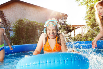 Happy kids playing in blue water of swimming pool