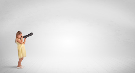 Cute little girl looking through spyglass to an empty space
