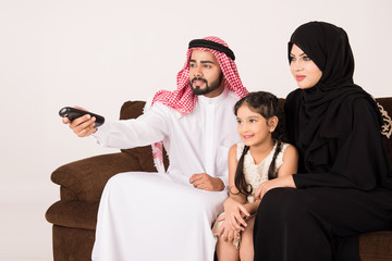 Fototapeta premium Arab family watching TV at home and using remote control