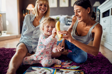 Cheerful kid taking banana from woman's hand