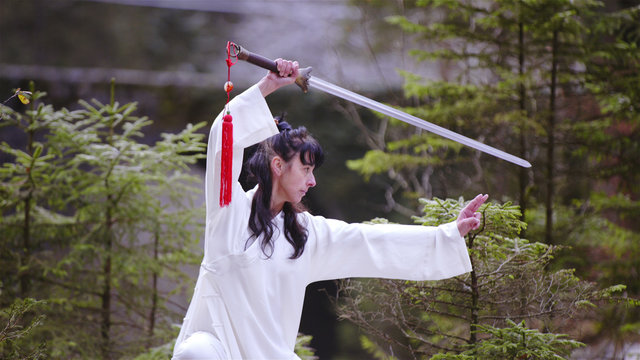 Woman in white kimono making a martial arts sword stance