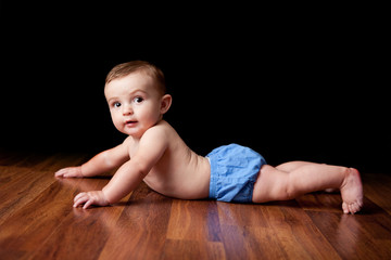 Naklejka premium Happy Baby Boy Lying on Wood Floor - Color Portrait